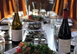 Red Stitch Wine bottles and wine tasting setup at a table.