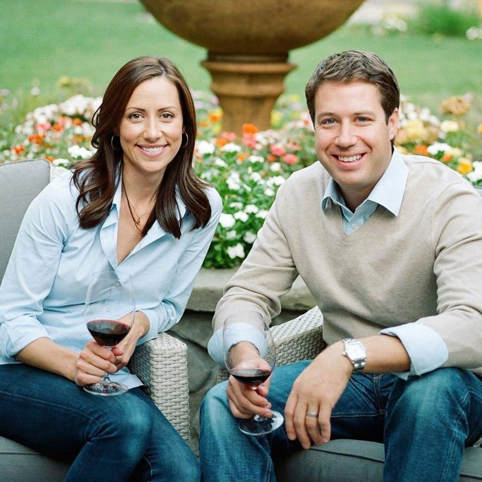 Couple enjoying red wine outdoors at a garden setting.